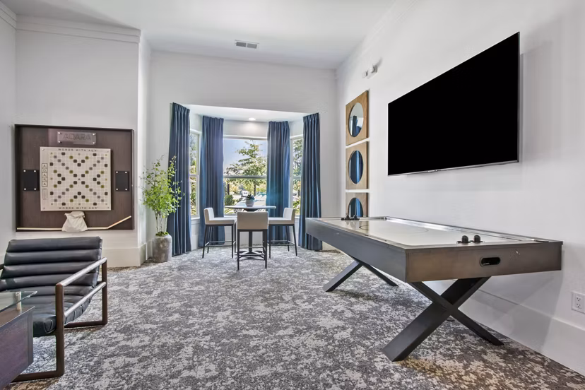 Game room with pool table and arcade games at Adara at Godley Station Apartments, offering fun recreational amenities for residents
