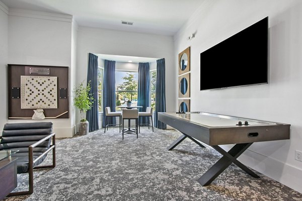 Game room with pool table and arcade games at Adara at Godley Station Apartments, offering fun recreational amenities for residents