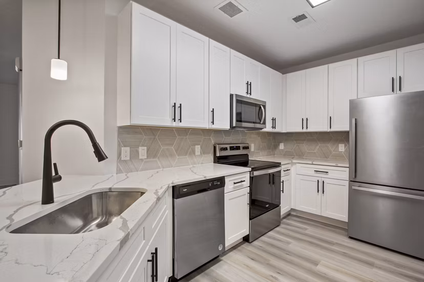 Modern kitchen with stainless steel appliances and granite countertops in Adara at Godley Station Apartments