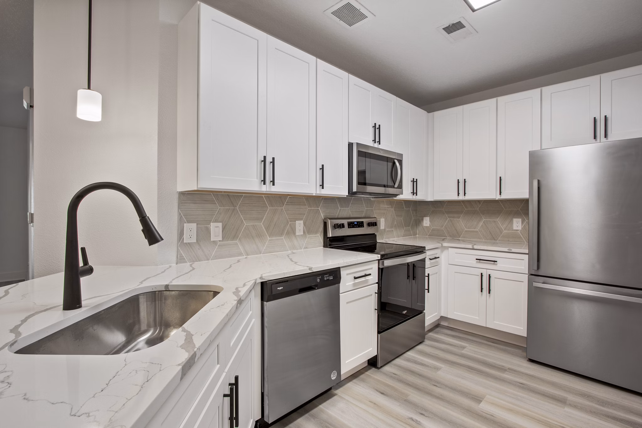 Modern kitchen with stainless steel appliances and granite countertops in Adara at Godley Station Apartments