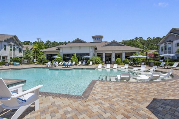 Resort-style pool area at Adara at Godley Station Apartments featuring lush landscaping