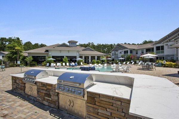 Outdoor grill station at Adara at Godley Station Apartments featuring modern BBQ amenities and seating, ideal for social gatherings