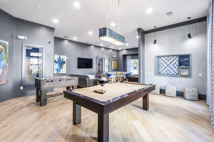 Clubhouse game room with billiards and seating in The Avenues at Verdier Pointe Apartments