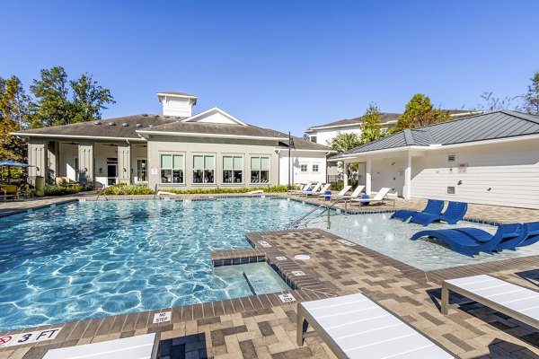 Relaxing outdoor pool area at The Avenues at Verdier Pointe Apartments with lush landscaping