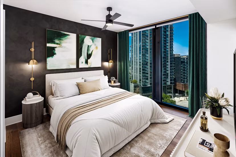 Bedroom with modern decor and large window at Nomia Apartments, offering a luxurious living experience in a vibrant community