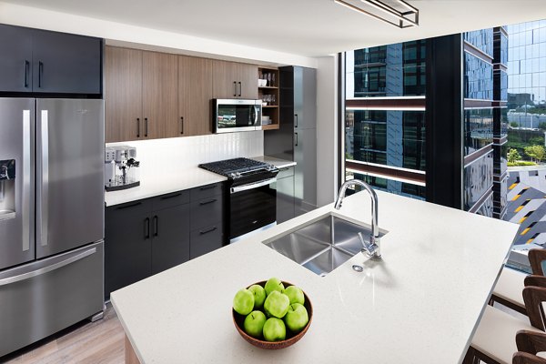 Modern kitchen with stainless steel appliances and quartz countertops in Nomia Apartments