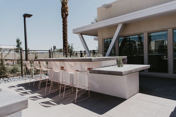 Tanager Apartments: Outdoor grill area with seating and greenery, perfect for gatherings in a stylish community setting