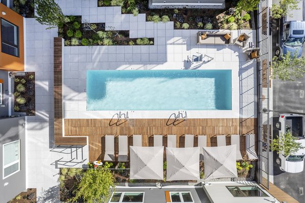 Modern outdoor pool with lounge chairs at Arris Apartments, ideal for relaxation and leisure in a luxury setting