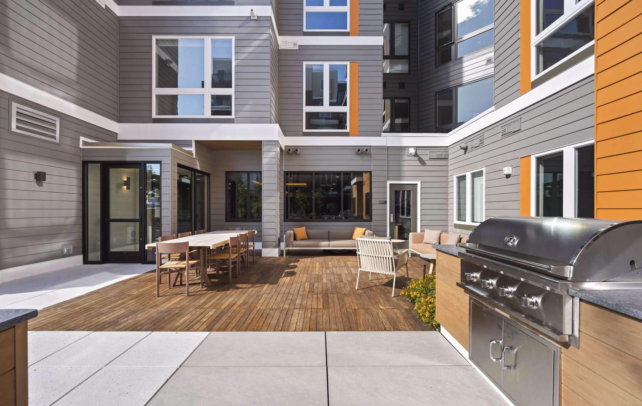 Grill area with modern seating and shade structures at Arris Apartments