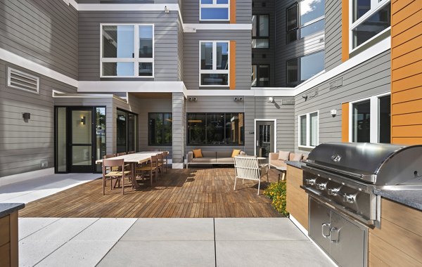 Grill area with modern seating and shade structures at Arris Apartments