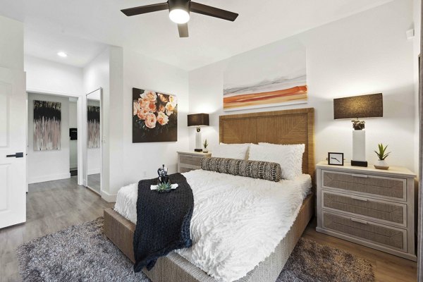 Sleek bedroom with modern decor at Nines at Kierland Apartments featuring stylish bedding and ample natural light
