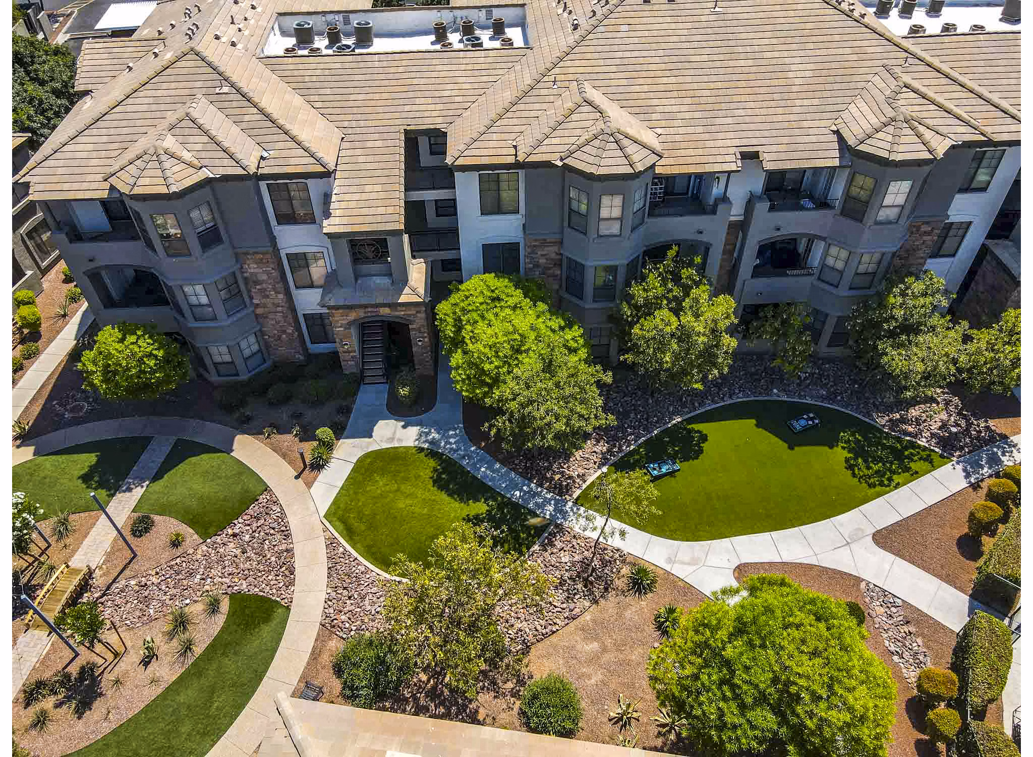 Aerial view of landscaped grounds with pathways and trees surrounding luxury apartments
