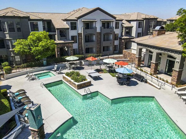 Luxury apartment complex with a swimming pool and relaxing lounge area in a sunny setting