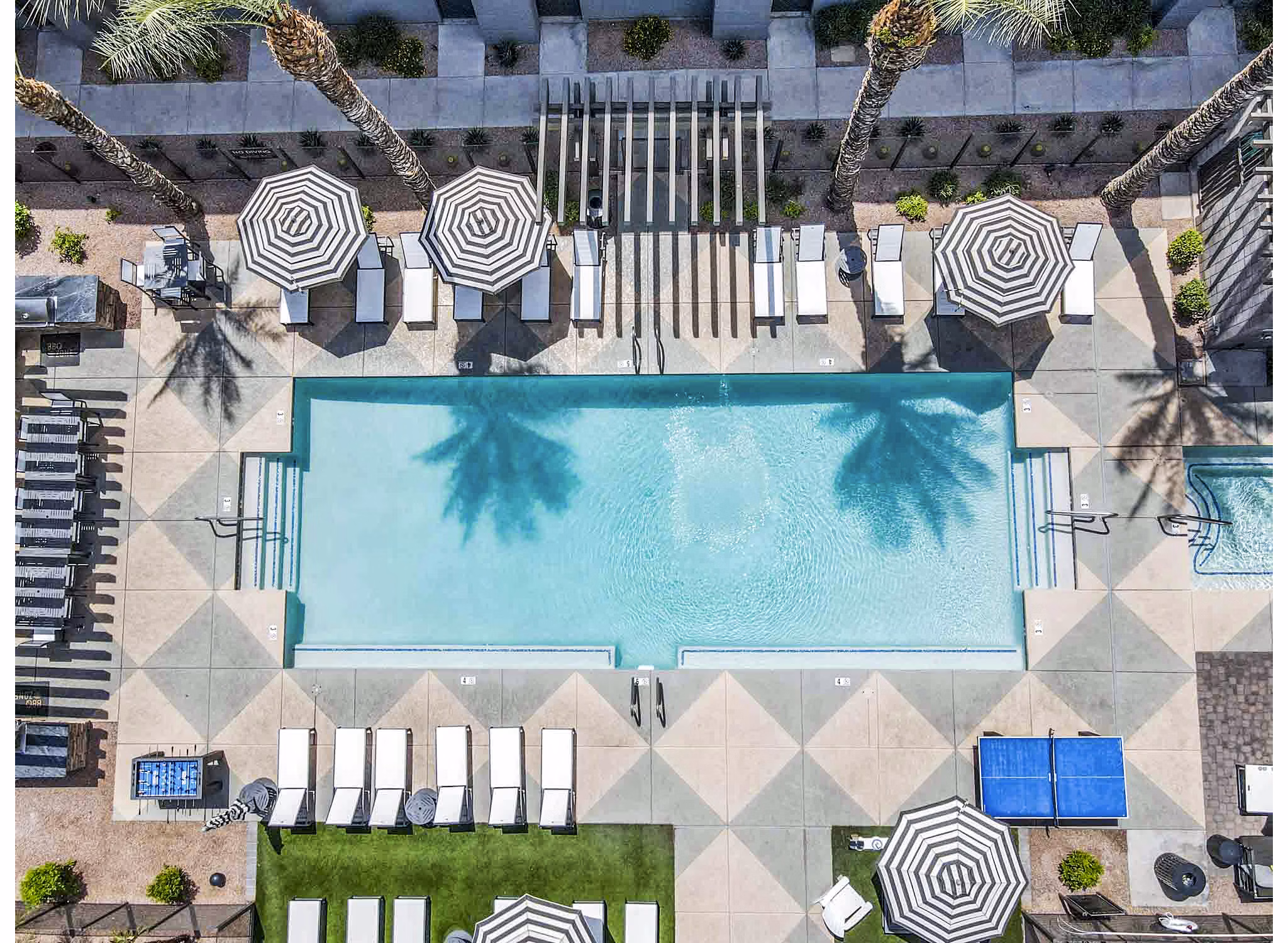 Outdoor swimming pool with lounge chairs and modern building in luxury apartments