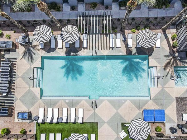 Outdoor swimming pool with lounge chairs and modern building in luxury apartments