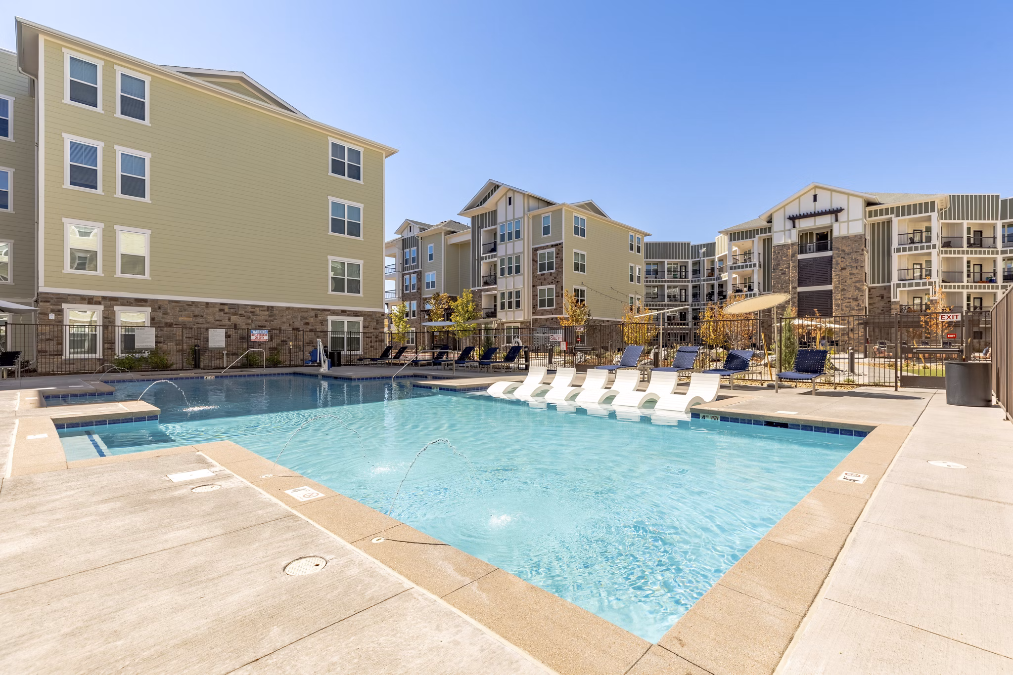 Resort-style pool at Five810 Southlands Apartments with lounge chairs and greenery in luxury community setting