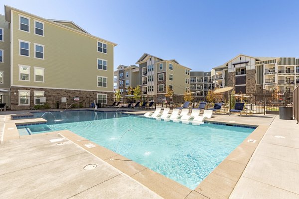 Resort-style pool at Five810 Southlands Apartments with lounge chairs and greenery in luxury community setting
