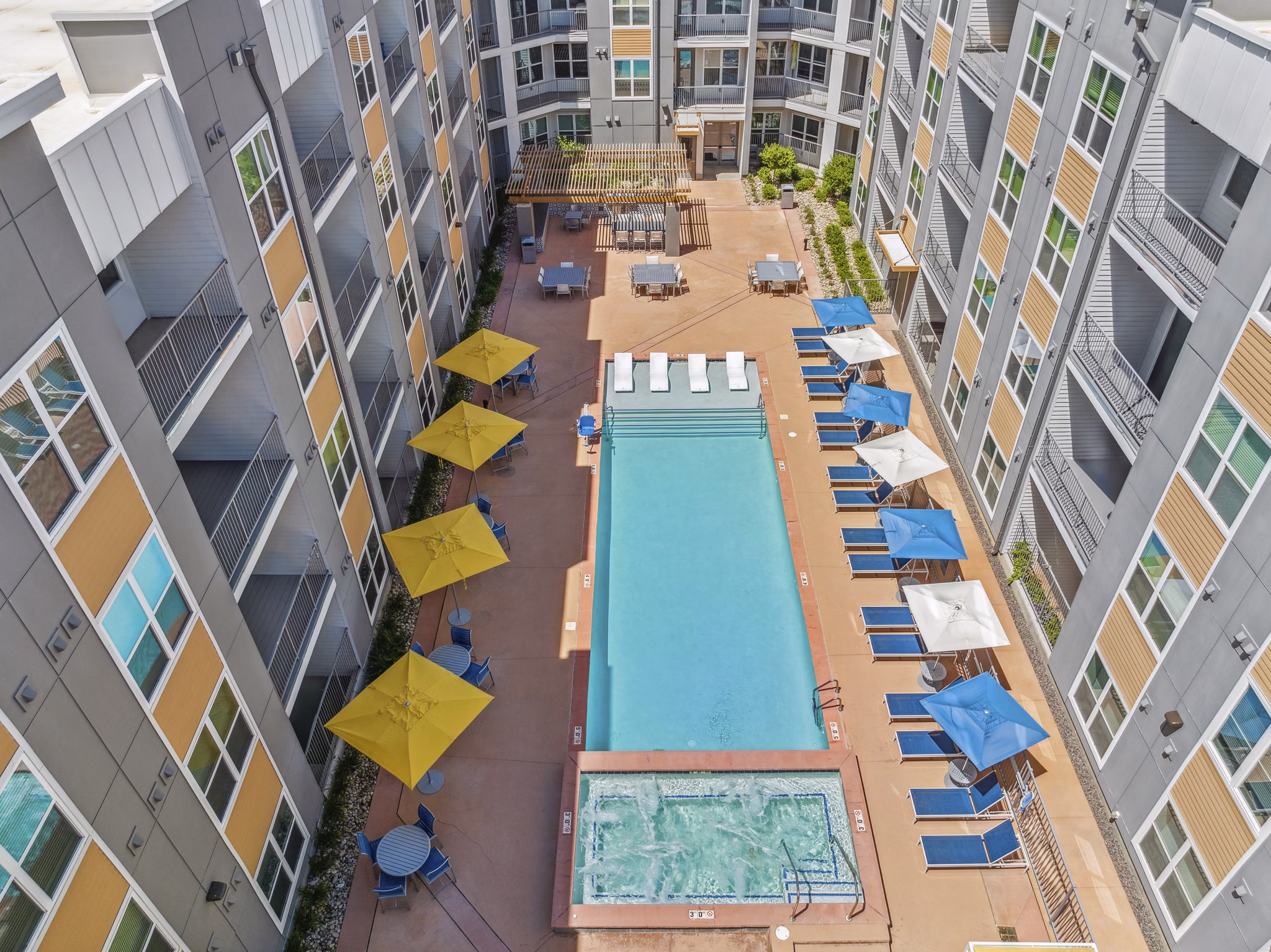 Outdoor pool with lounge chairs at Mezz at Fiddler's Green Apartments, offering luxury living in a scenic setting