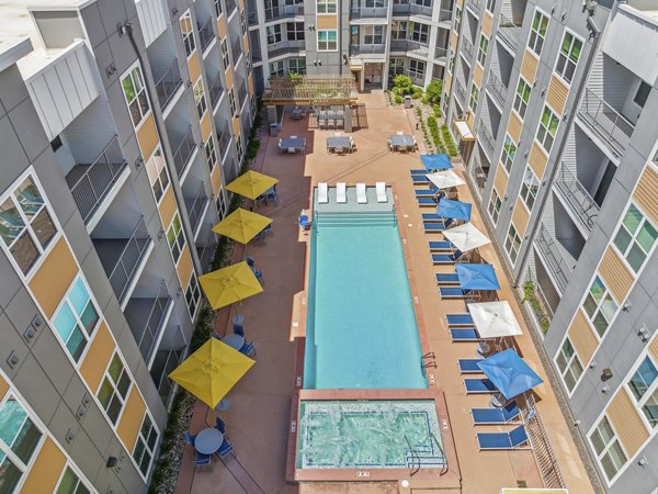 Outdoor pool with lounge chairs at Mezz at Fiddler's Green Apartments, offering luxury living in a scenic setting