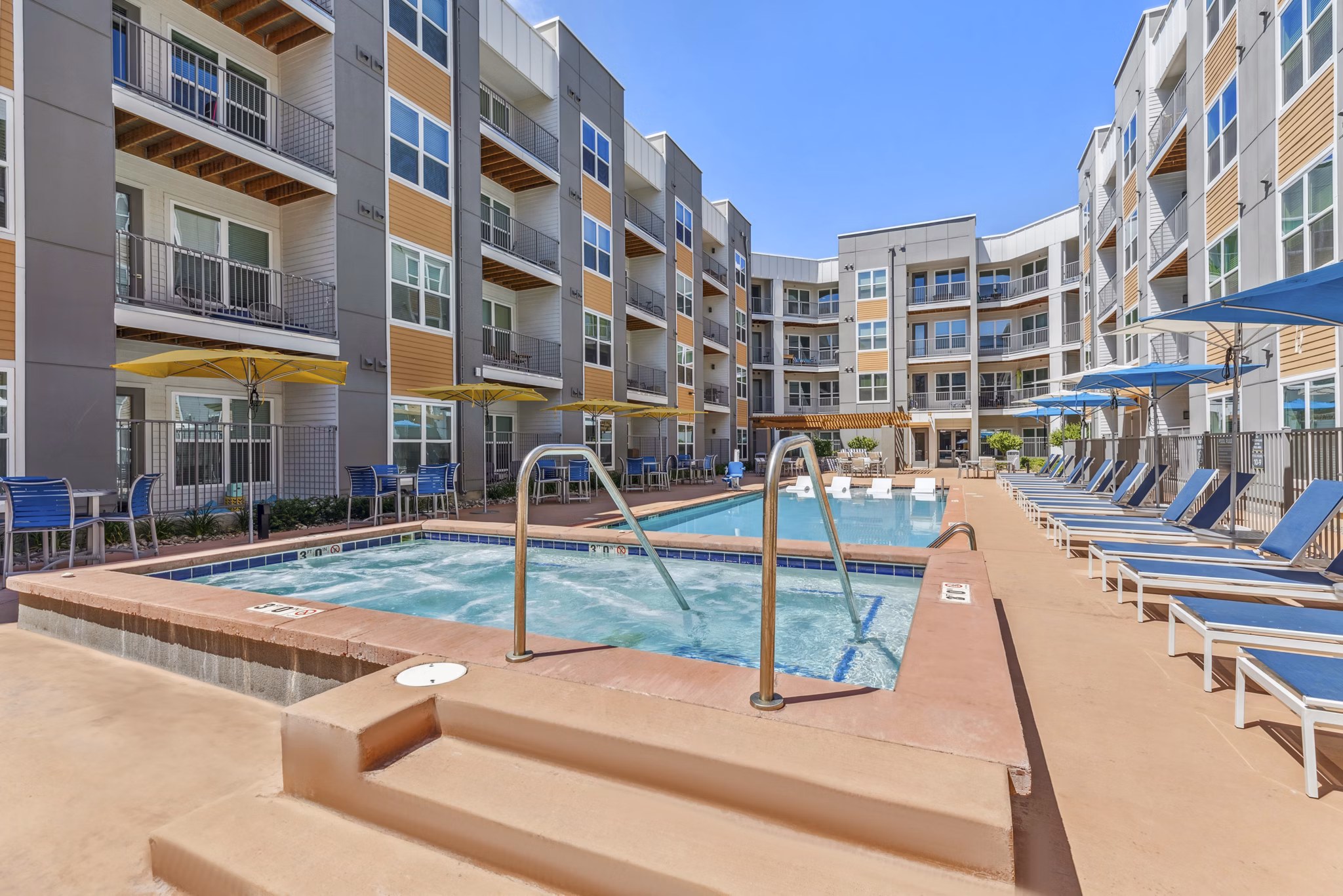 Resort-style outdoor pool at Mezz at Fiddler's Green Apartments, featuring lounge chairs and landscaped surroundings