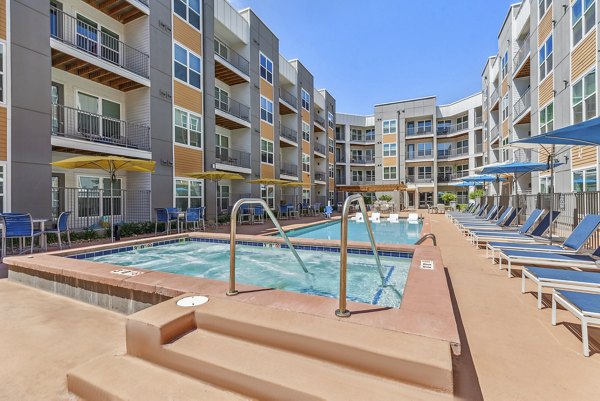 Resort-style outdoor pool at Mezz at Fiddler's Green Apartments, featuring lounge chairs and landscaped surroundings
