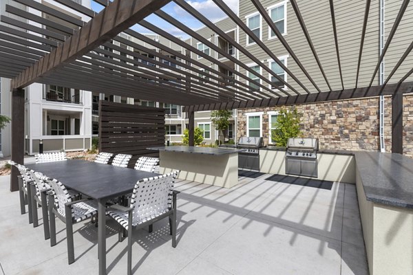 Grill area with modern outdoor seating at The Zeb Apartments, perfect for hosting gatherings in a luxury urban setting