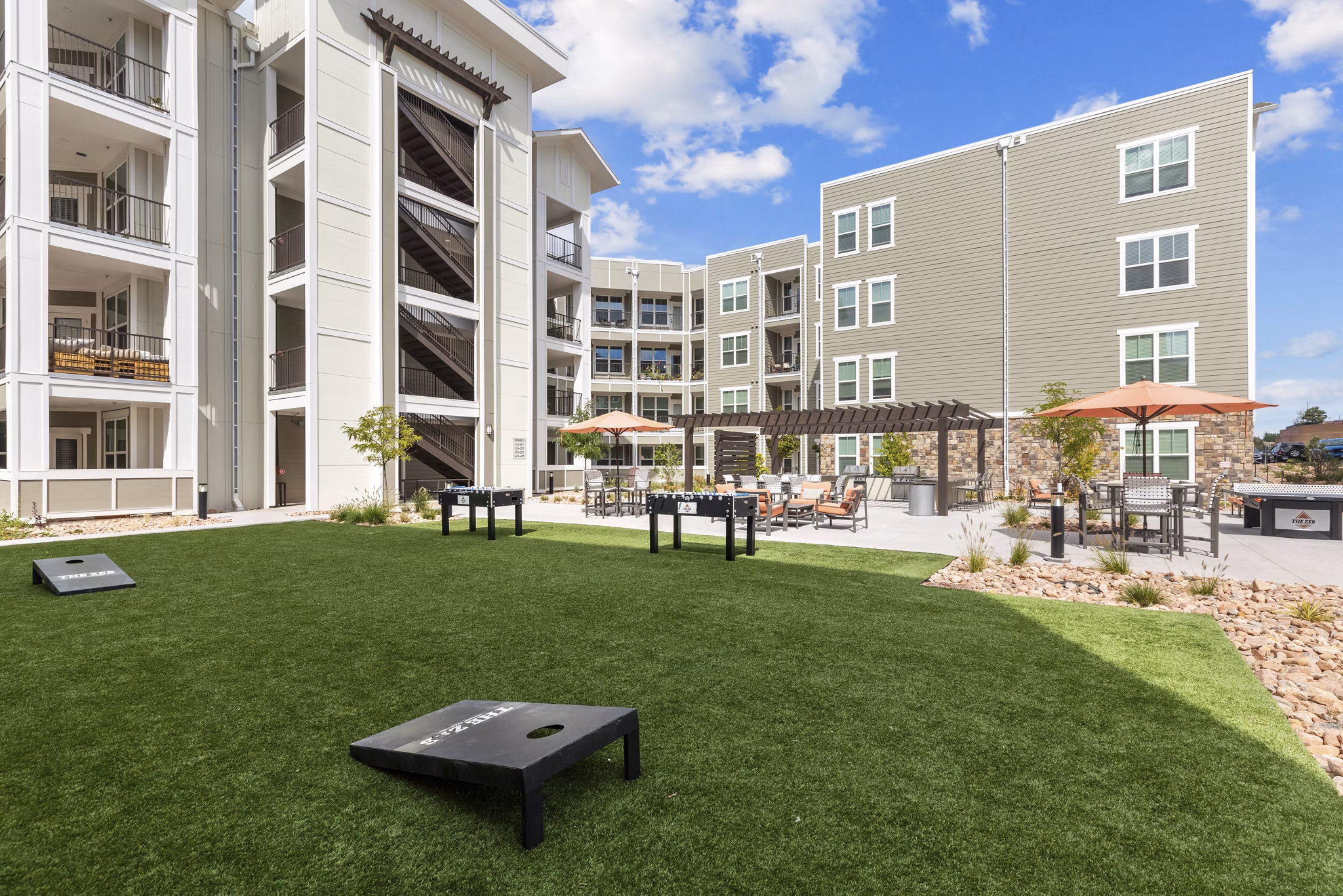 The Zeb Apartments: Spacious courtyard with lush greenery and seating areas in a luxury apartment community