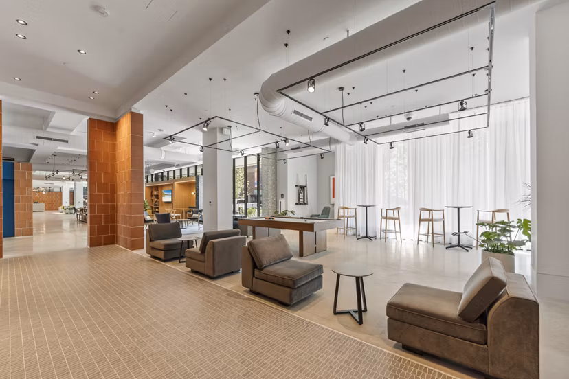 Clubhouse with modern furnishings and large window views at The Clark Apartments, a Greystar luxury community