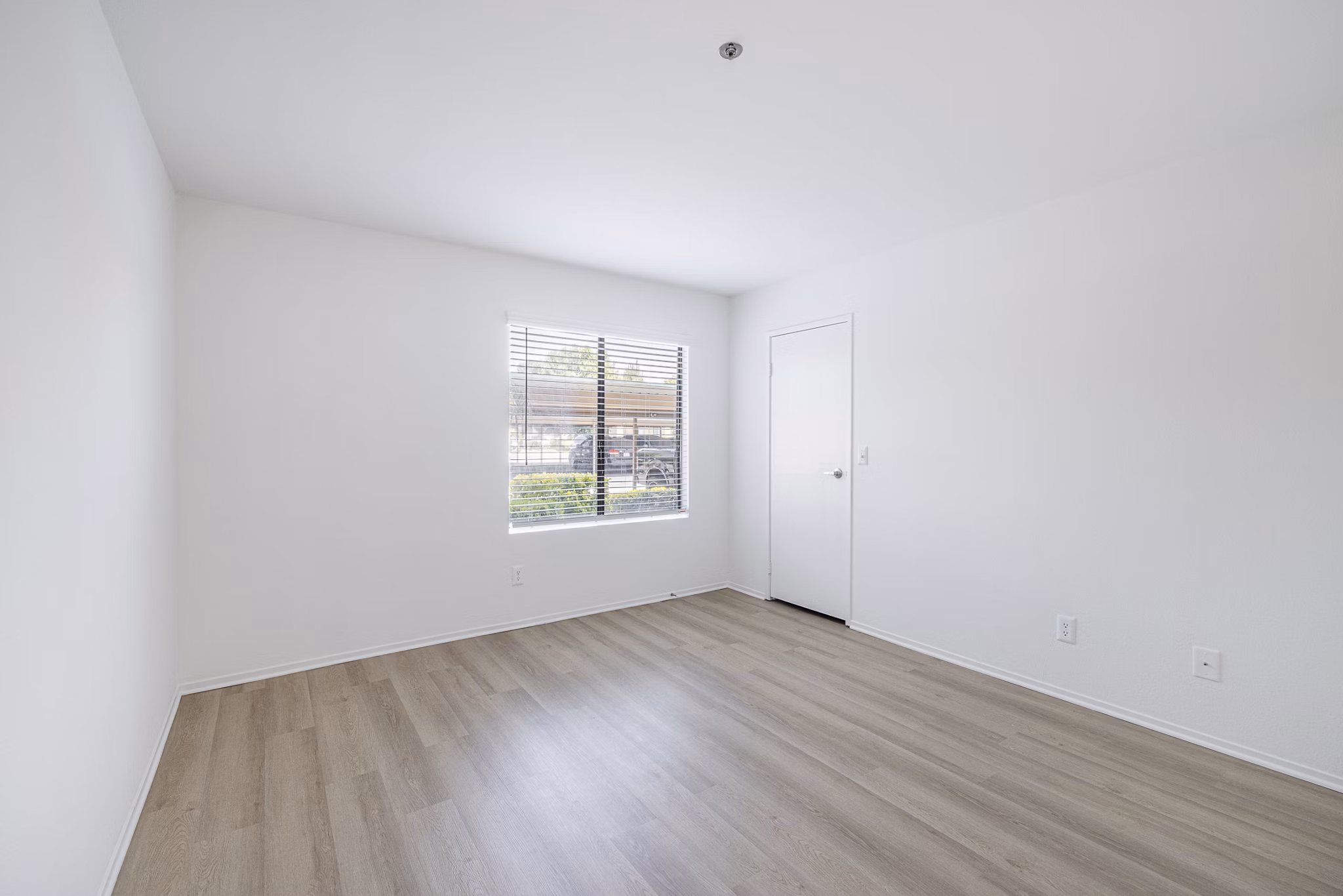 Cozy bedroom with neutral decor and large window at The Landing Apartments, offering luxury living in a serene environment