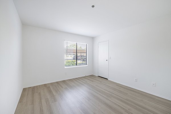 Cozy bedroom with neutral decor and large window at The Landing Apartments, offering luxury living in a serene environment