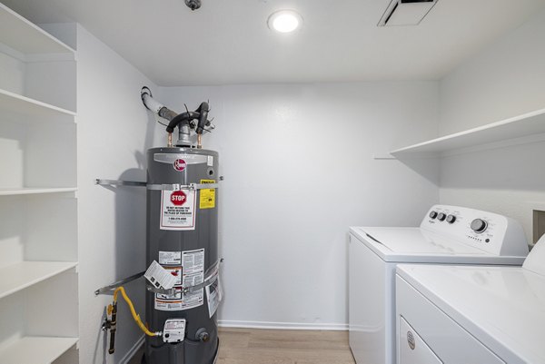 Laundry room with modern appliances at The Landing Apartments featuring ample storage and folding space