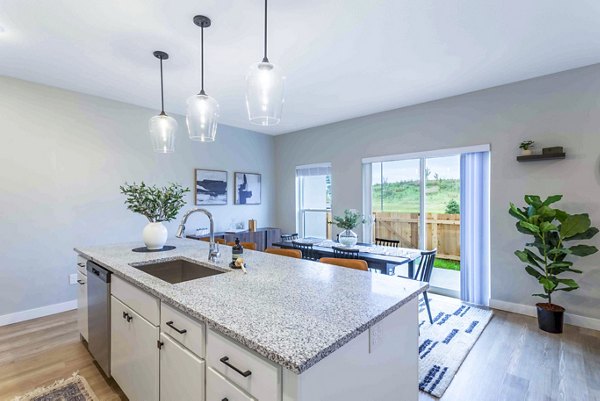 Modern kitchen with stainless steel appliances and granite countertops in Summerwell Maple Grove Townhouses