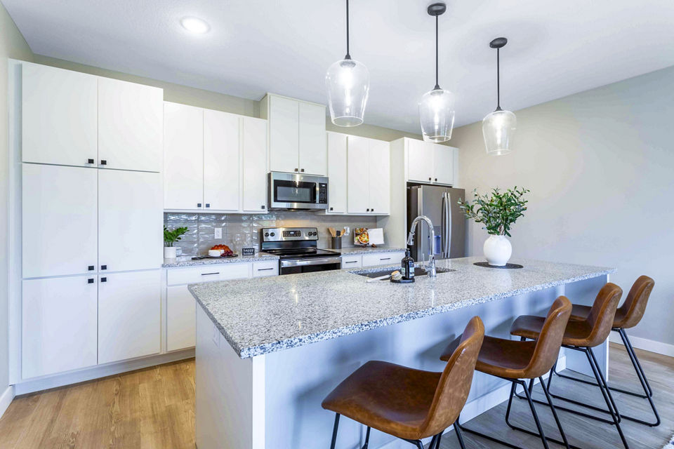 Modern kitchen featuring stainless steel appliances and granite countertops in Summerwell Maple Grove Townhouses