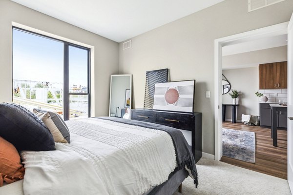 Cozy bedroom with plush bedding at The Eddi Apartments, featuring modern decor and abundant natural light