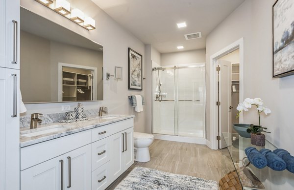 Modern bathroom with marble countertops and glass shower in The Westlyn Apartments