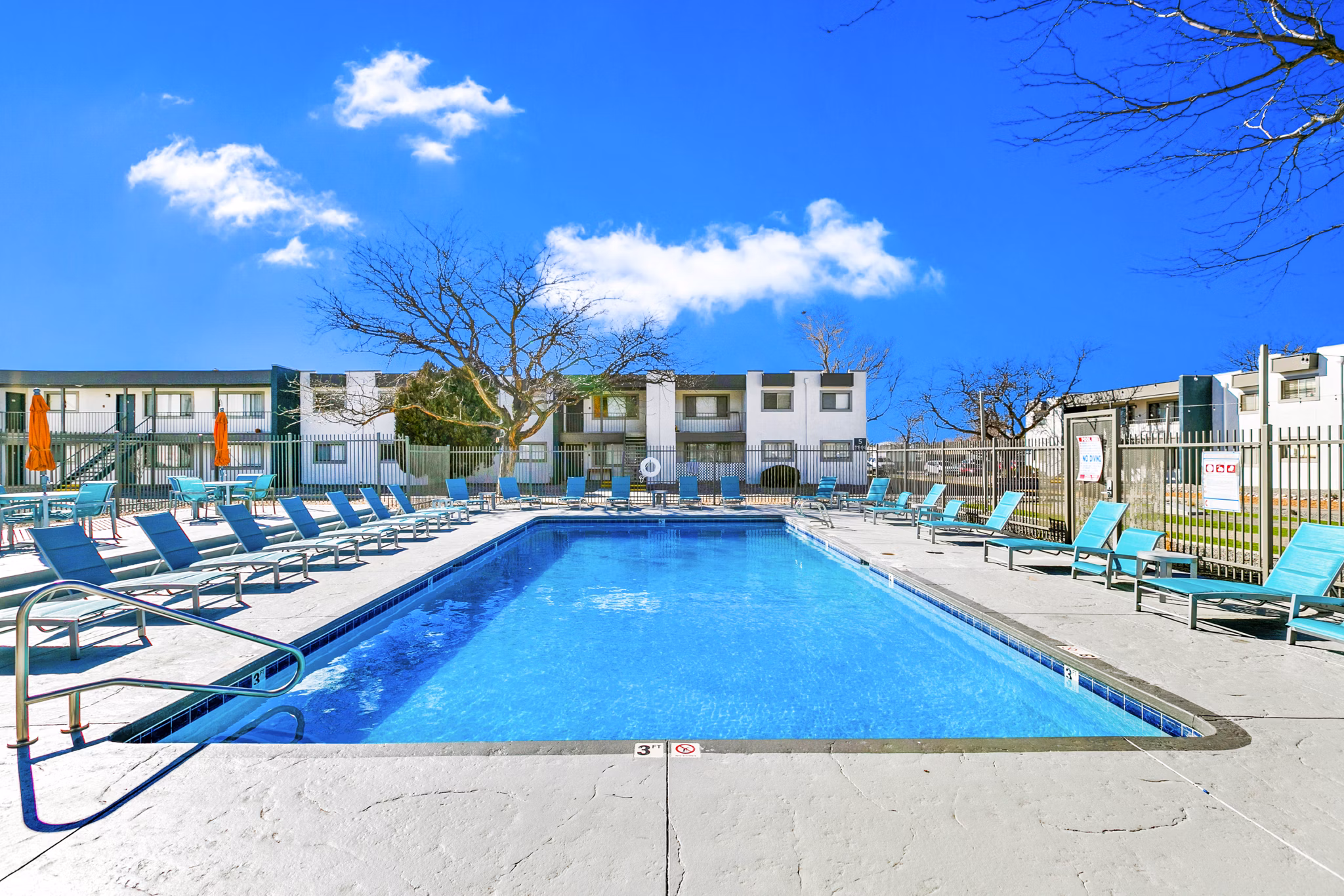 Modern pool area at Tesota Four Hills Apartments with lounge chairs and umbrellas, offering a luxury living experience