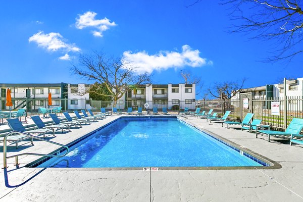 Modern pool area at Tesota Four Hills Apartments with lounge chairs and umbrellas, offering a luxury living experience