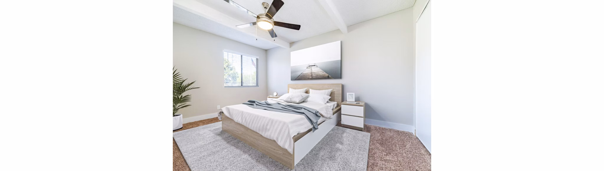 Bedroom with modern decor and large windows in Tesota Morningside Apartments