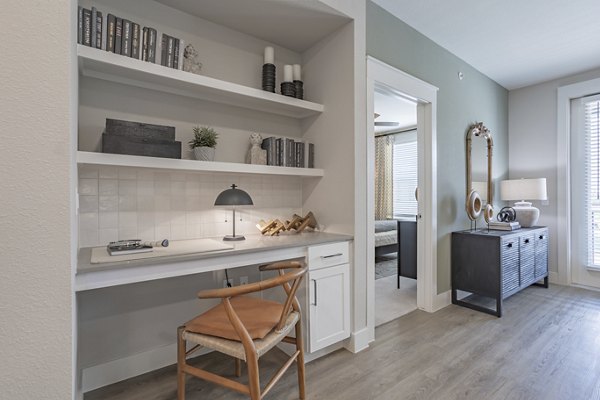 Home office with ergonomic chair and large desk in Filament Apartments Ideal for remote work with modern dÃ©cor and ample natural light