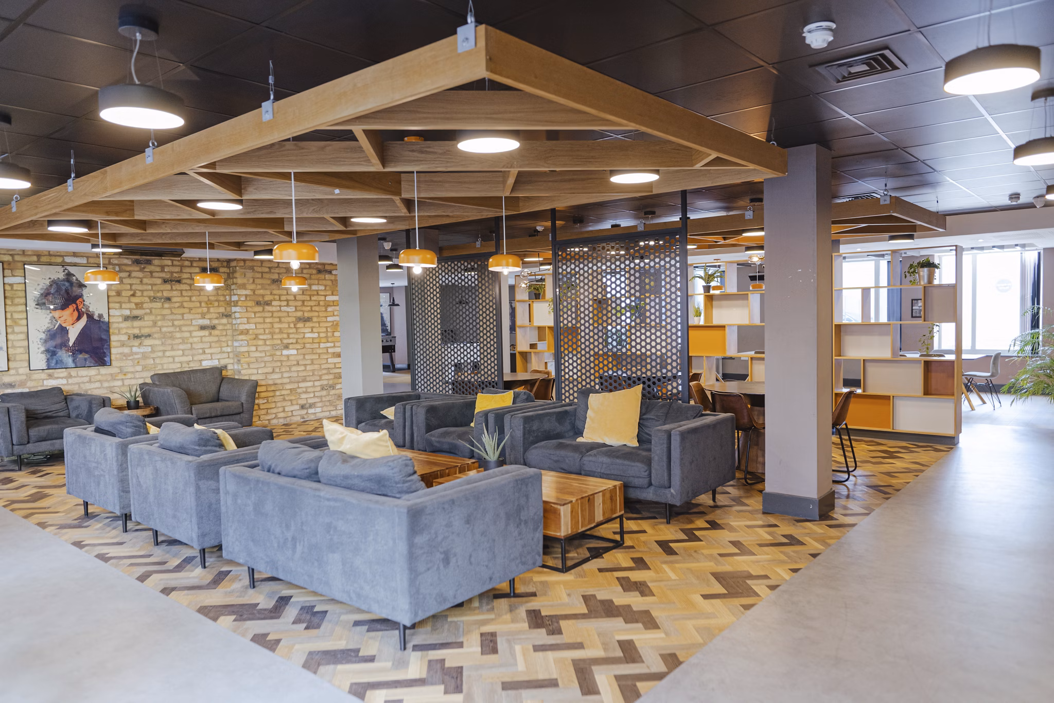 Lounge area at Canvas The Heights apartments, featuring stylish gray seating, warm lighting, and a modern industrial design with exposed brick walls and wood accents.