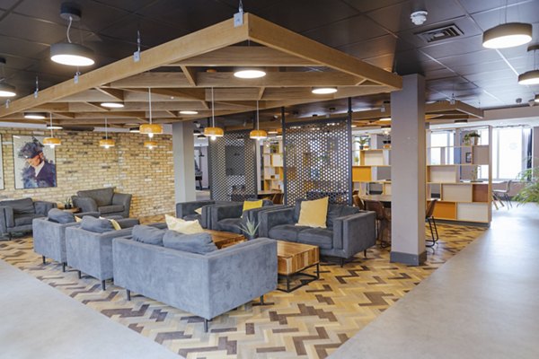 Lounge area at Canvas The Heights apartments, featuring stylish gray seating, warm lighting, and a modern industrial design with exposed brick walls and wood accents.