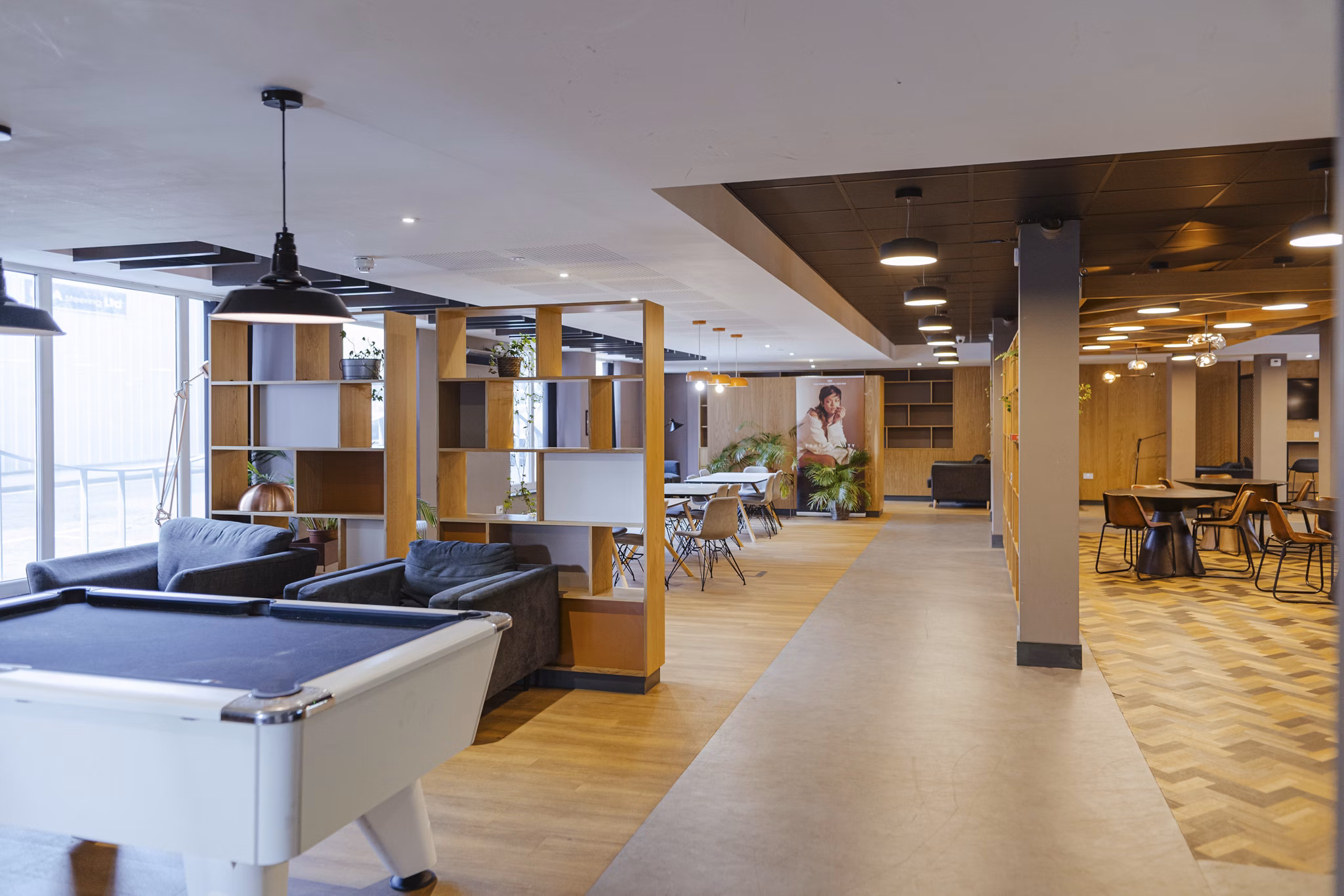 Game room at Canvas The Heights apartments, featuring a pool table, modern seating areas, and an open layout with wood accents and contemporary lighting.