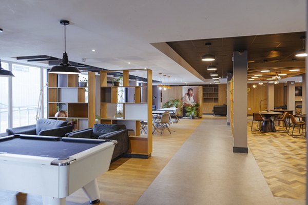 Game room at Canvas The Heights apartments, featuring a pool table, modern seating areas, and an open layout with wood accents and contemporary lighting.