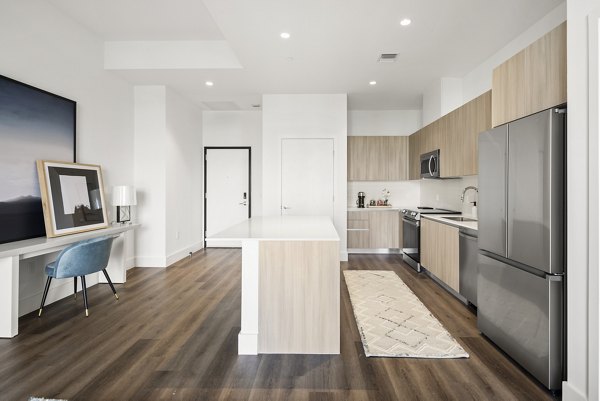 Modern kitchen with stainless steel appliances and island seating at Grove Central Residences Apartments