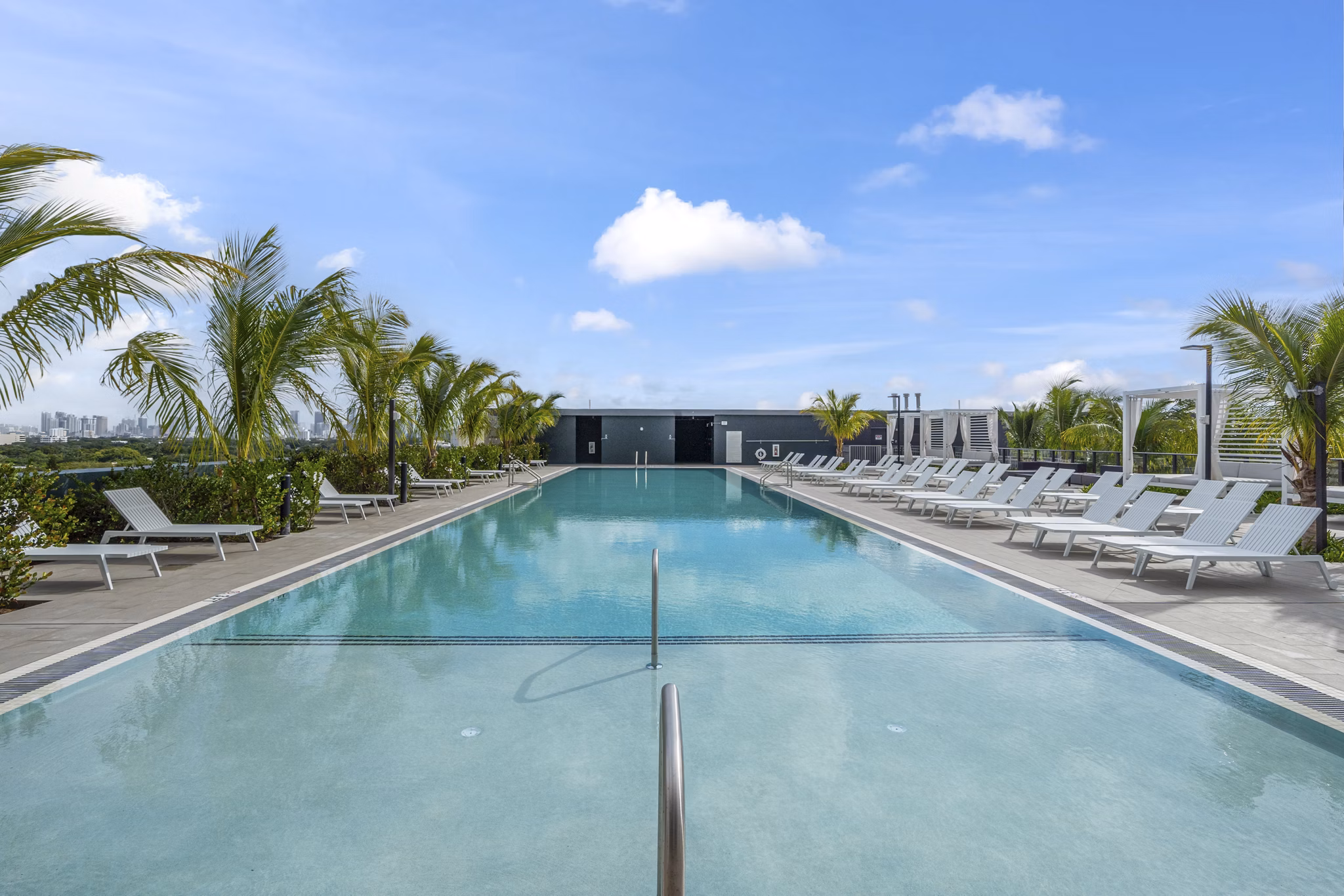 Relaxing outdoor pool with lounge chairs at Grove Central Residences Apartments, perfect for summer leisure and recreation