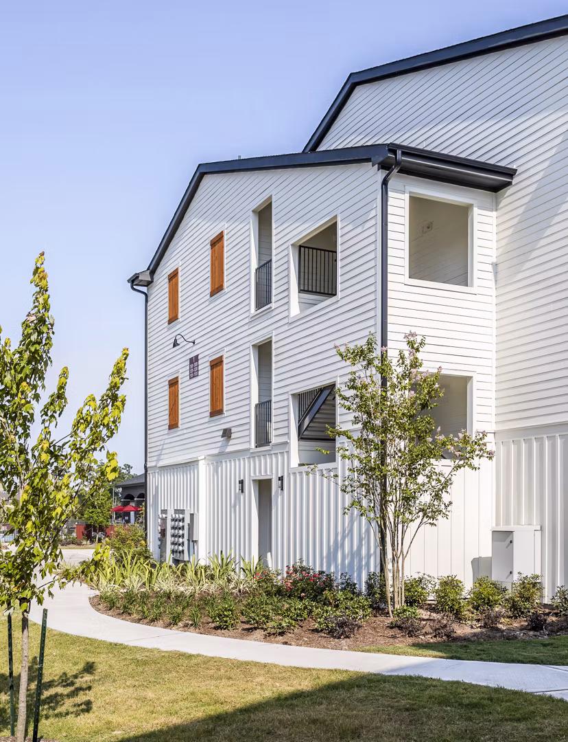 Modern multi-story luxury apartments with white siding and wooden accents in a landscaped setting