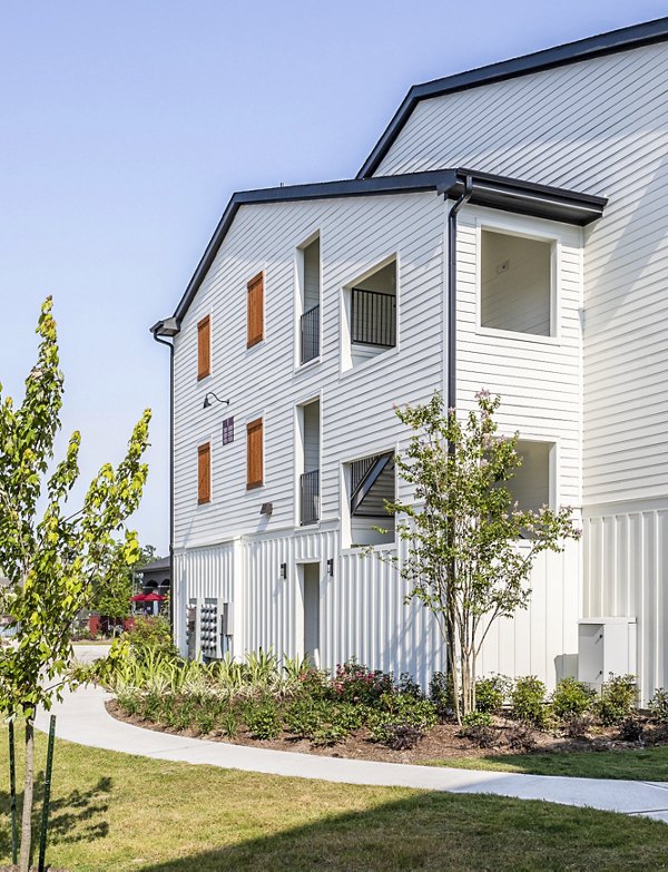 Modern multi-story luxury apartments with white siding and wooden accents in a landscaped setting