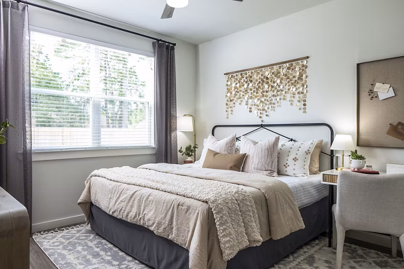 Spacious bedroom with comfortable bed and natural light from window curtains in luxury apartments