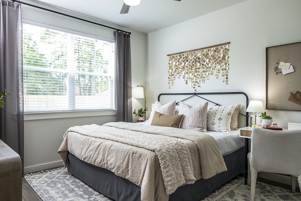 Spacious bedroom with comfortable bed and natural light from window curtains in luxury apartments