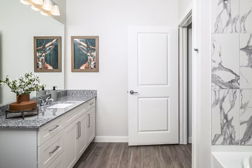 Modern bathroom featuring granite countertop and bathtub with marble tiles in luxury apartment